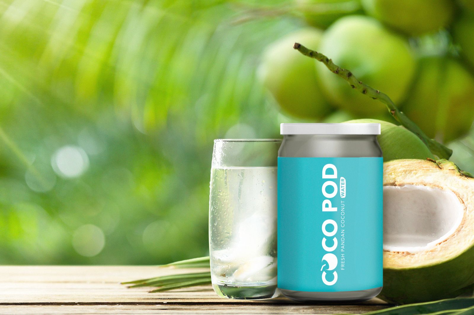 A Cocopod pod of fresh pandan coconut water beside a glass and an opened green coconut
